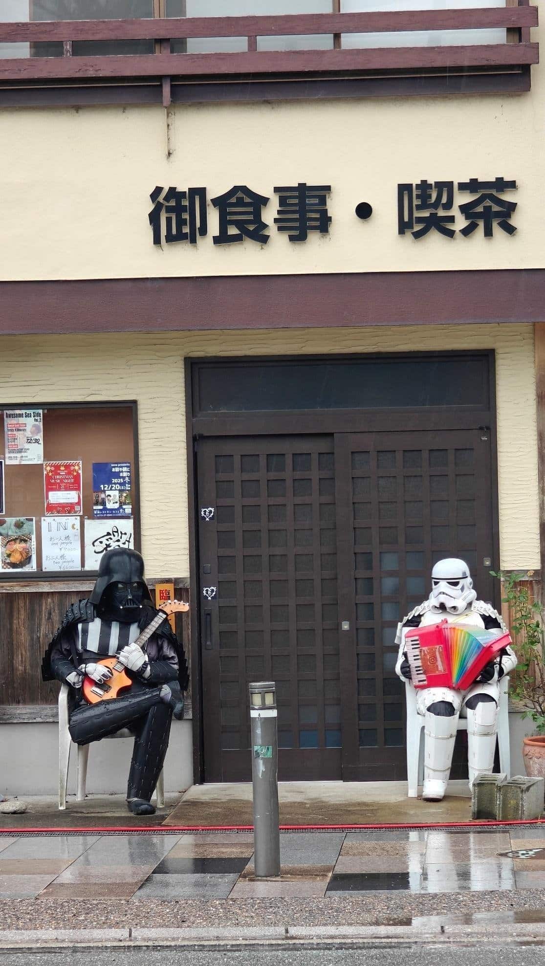 Figures in costumes play instruments outside cafe