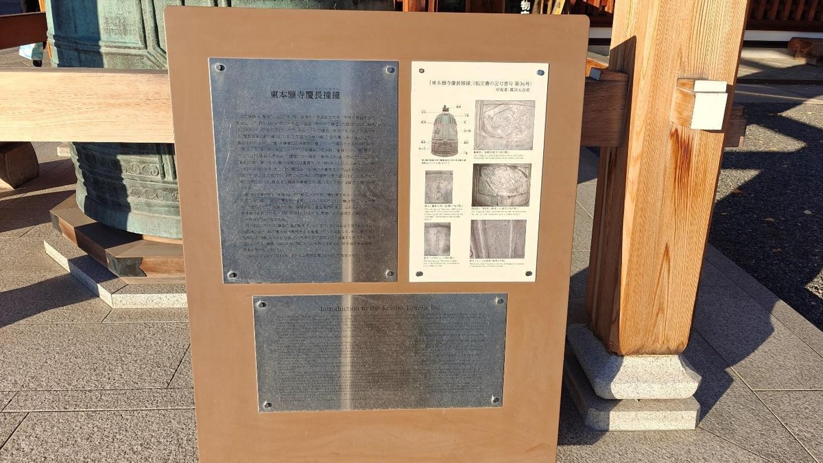 Informational plaque beside large bronze bell