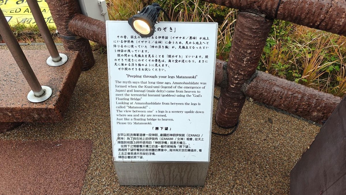 Informational sign on wooden walkway with light above