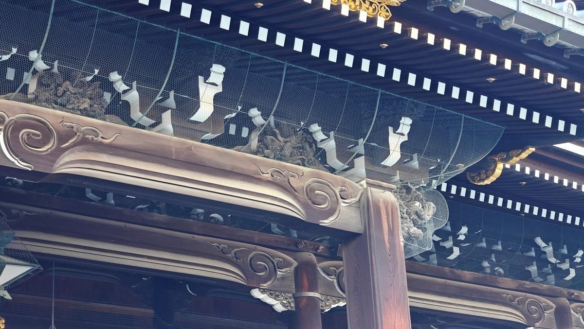 Intricate wooden temple carvings with decorative mesh fencing