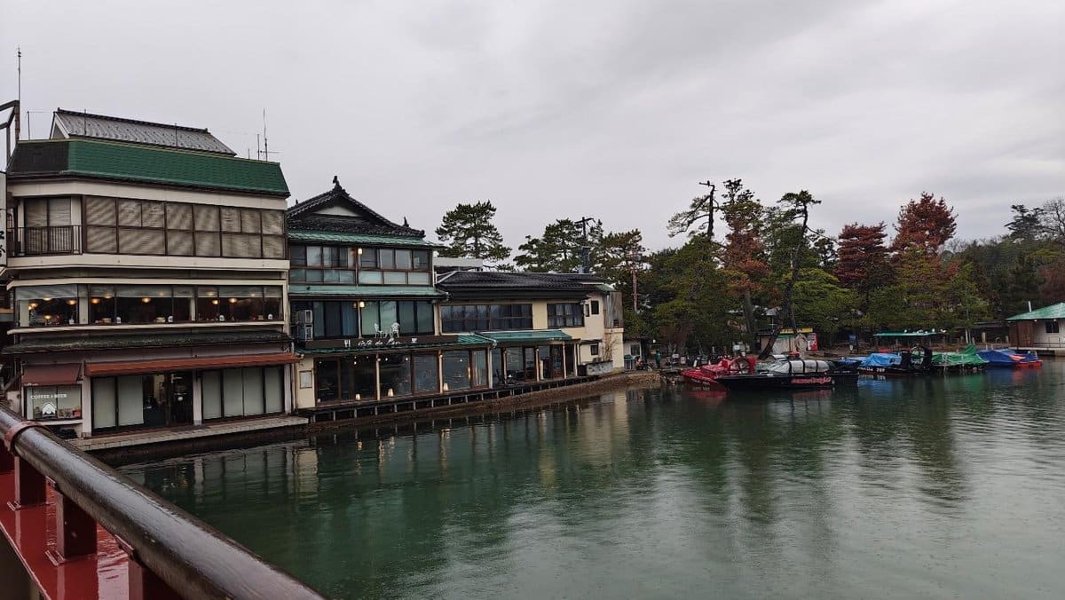 Japanese lakefront buildings with boats and autumn trees