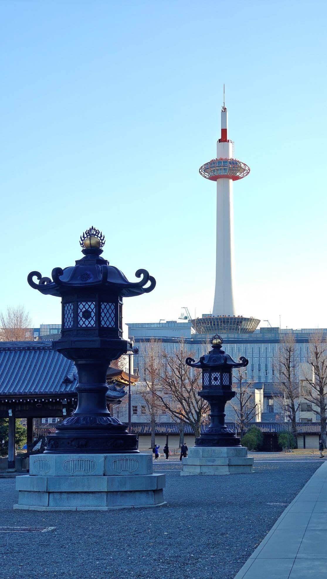 Kyoto Tower and traditional lanterns under clear blue sky