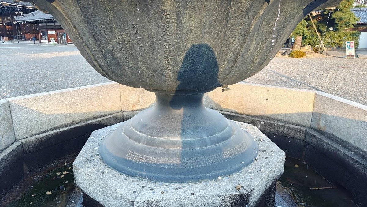 Large stone sculpture with shadow, droplets falling, serene ambiance