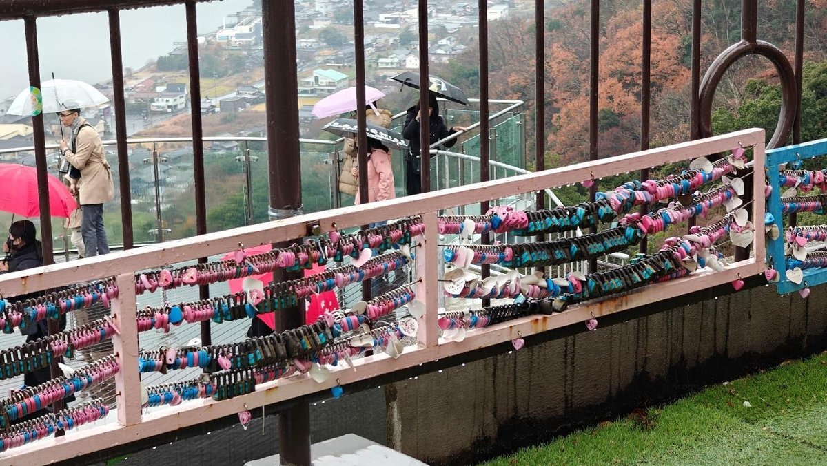 Love locks on bridge with scenic view and umbrellas in rain