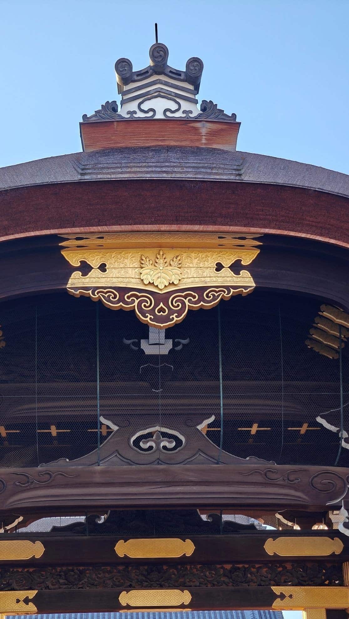 Ornate wooden temple roof with gold accents against blue sky