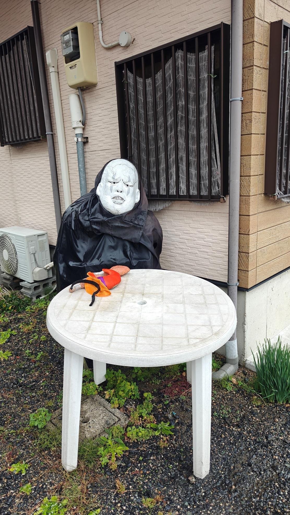 Outdoor mannequin with white mask next to round table