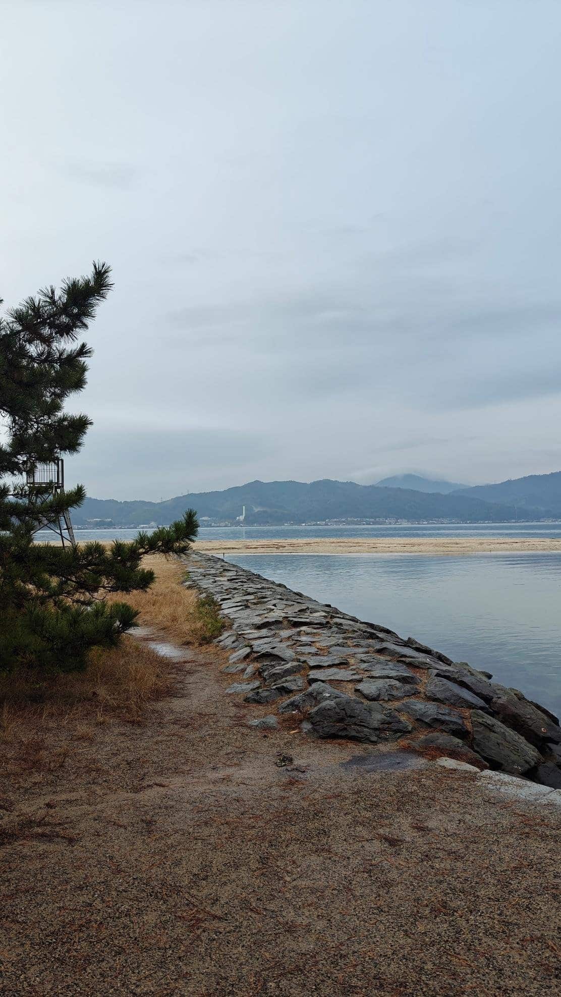 Path by rocky shoreline with distant mountains