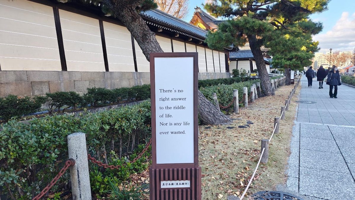 Pathway with signboard beside traditional building and trees