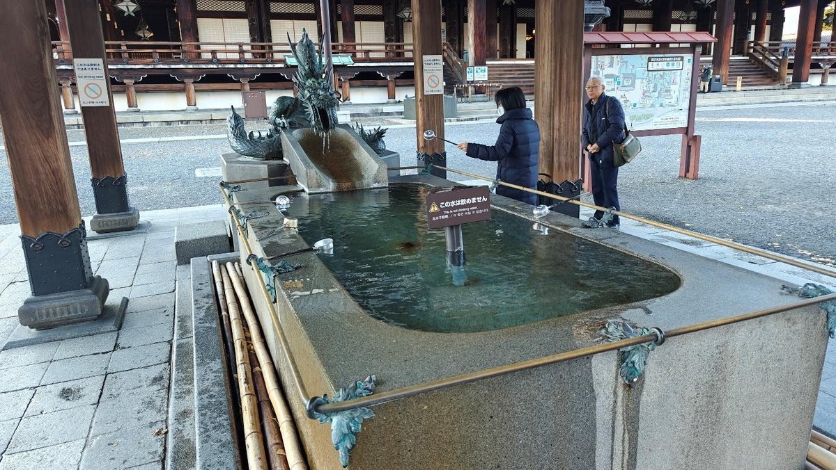 People at temple water basin with dragon sculpture
