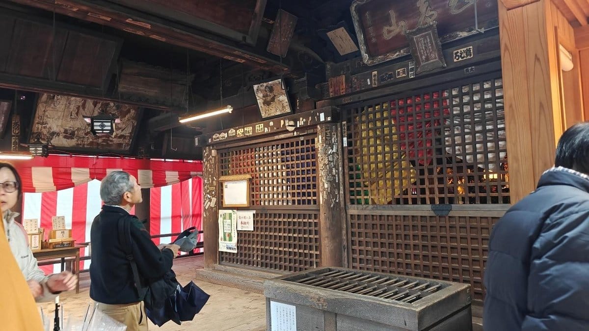 People inside a decorated wooden shrine with red and white curtains