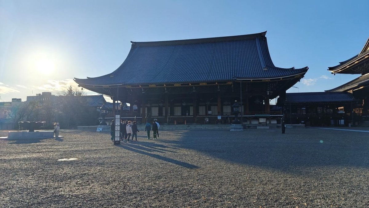 People near a historic temple building in sunlight