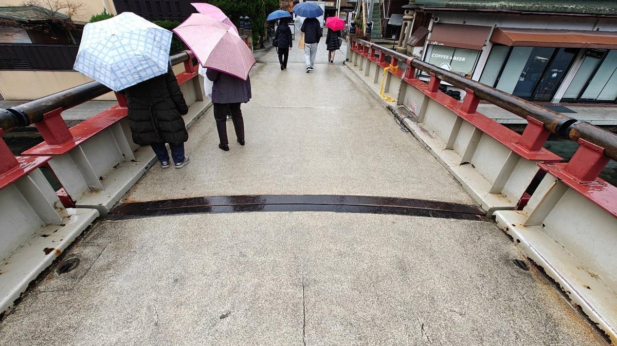 People with umbrellas crossing a rainy bridge