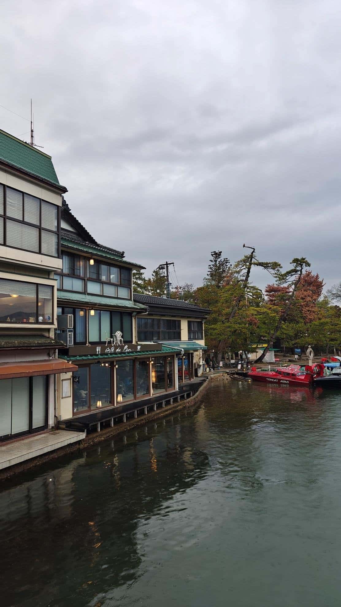 Riverside buildings with boats under cloudy sky