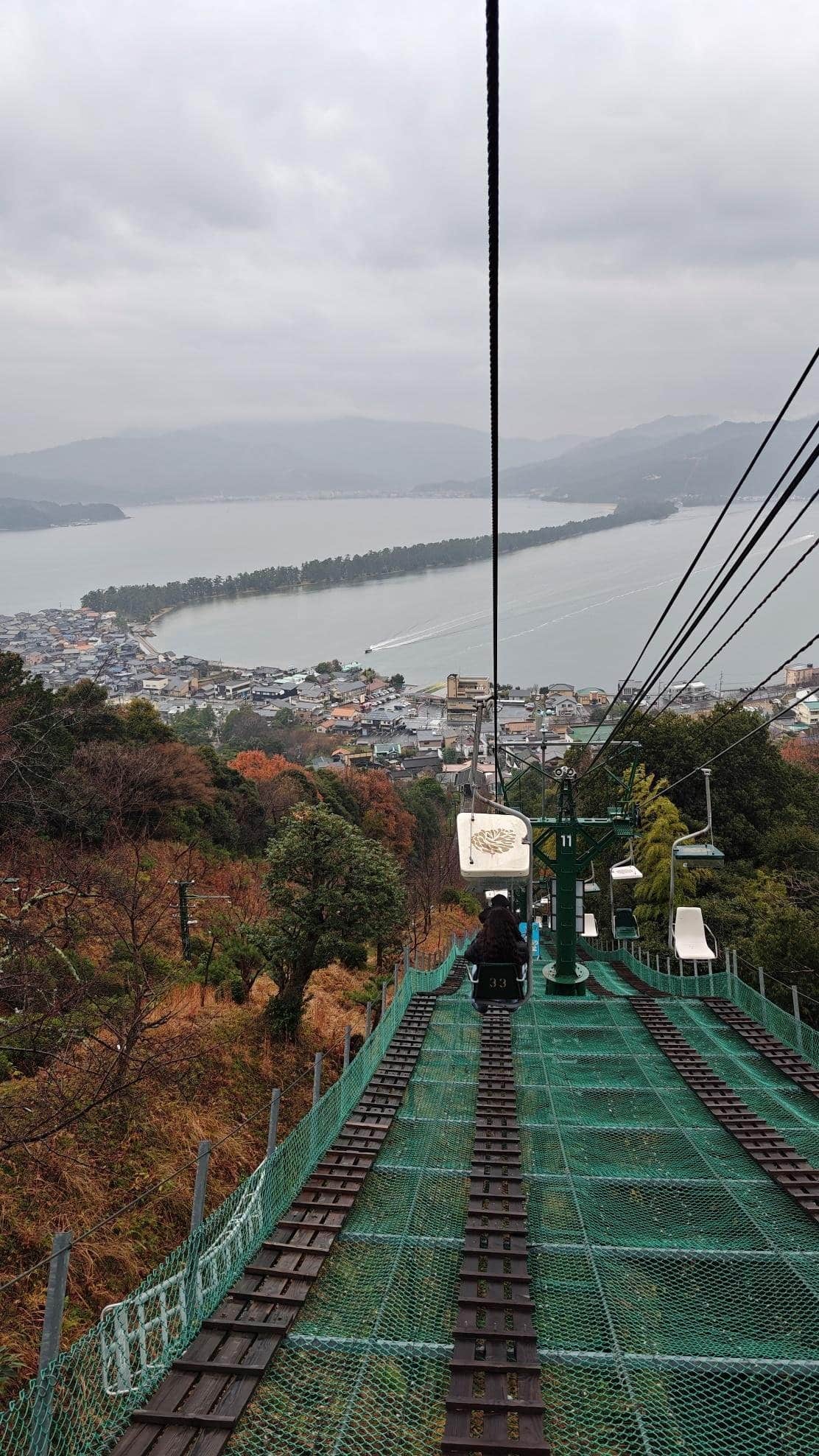 Scenic chairlift view over bay with misty mountains