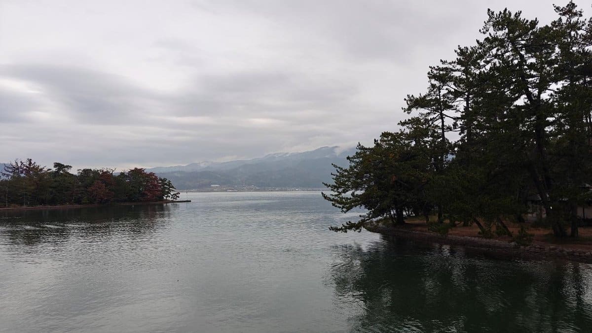 Serene lake with trees and mountains under cloudy sky