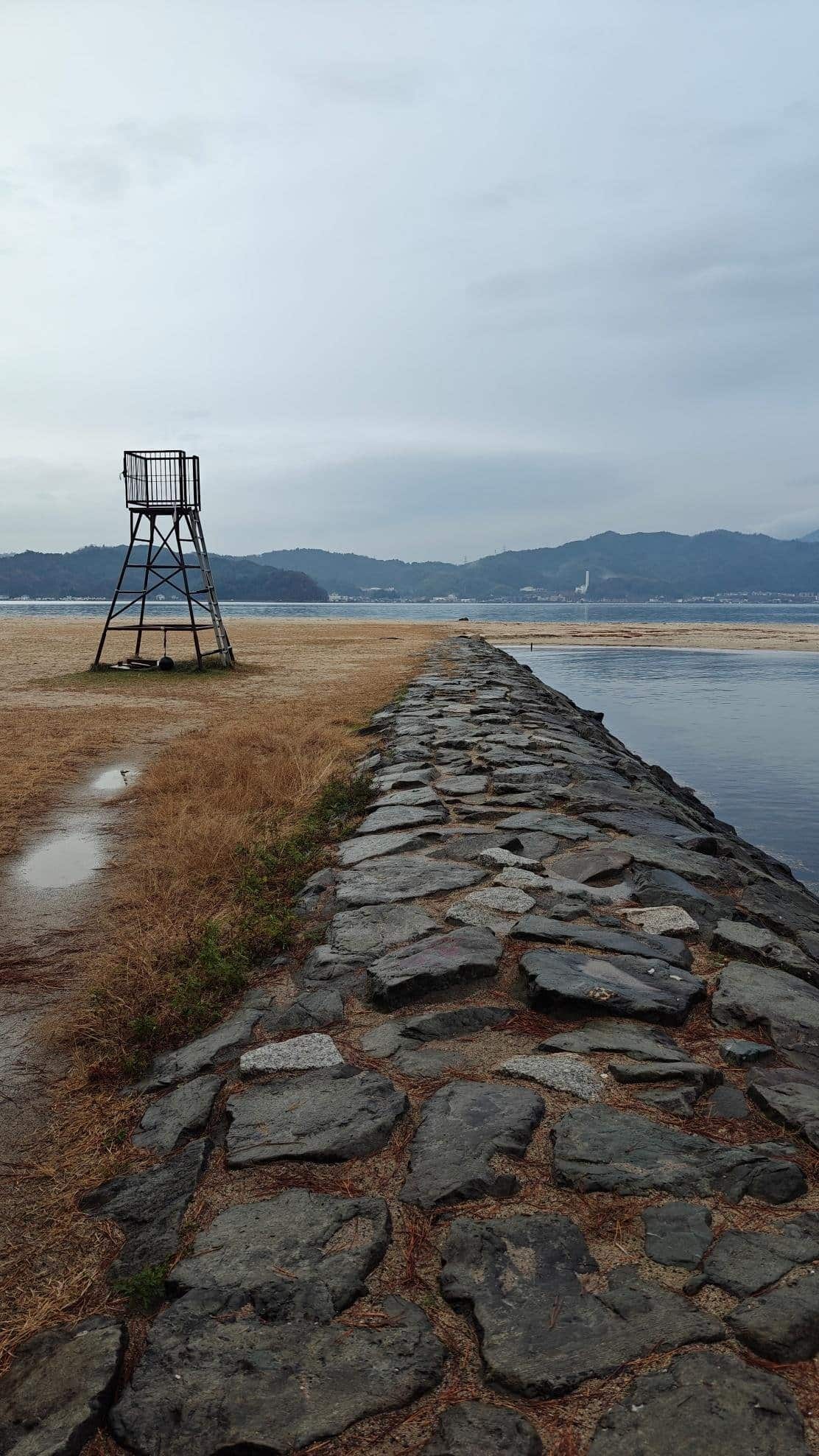 Stone path leading to water with mountains and lifeguard tower