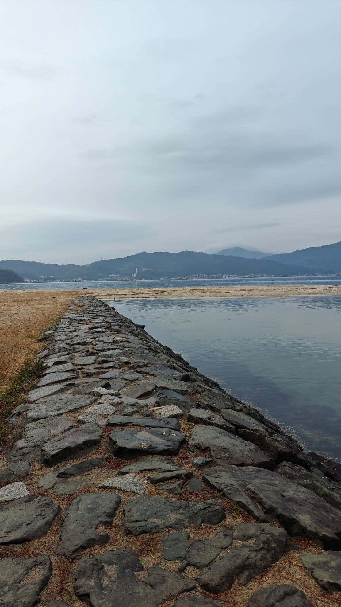 Stone pathway along tranquil water with distant mountains