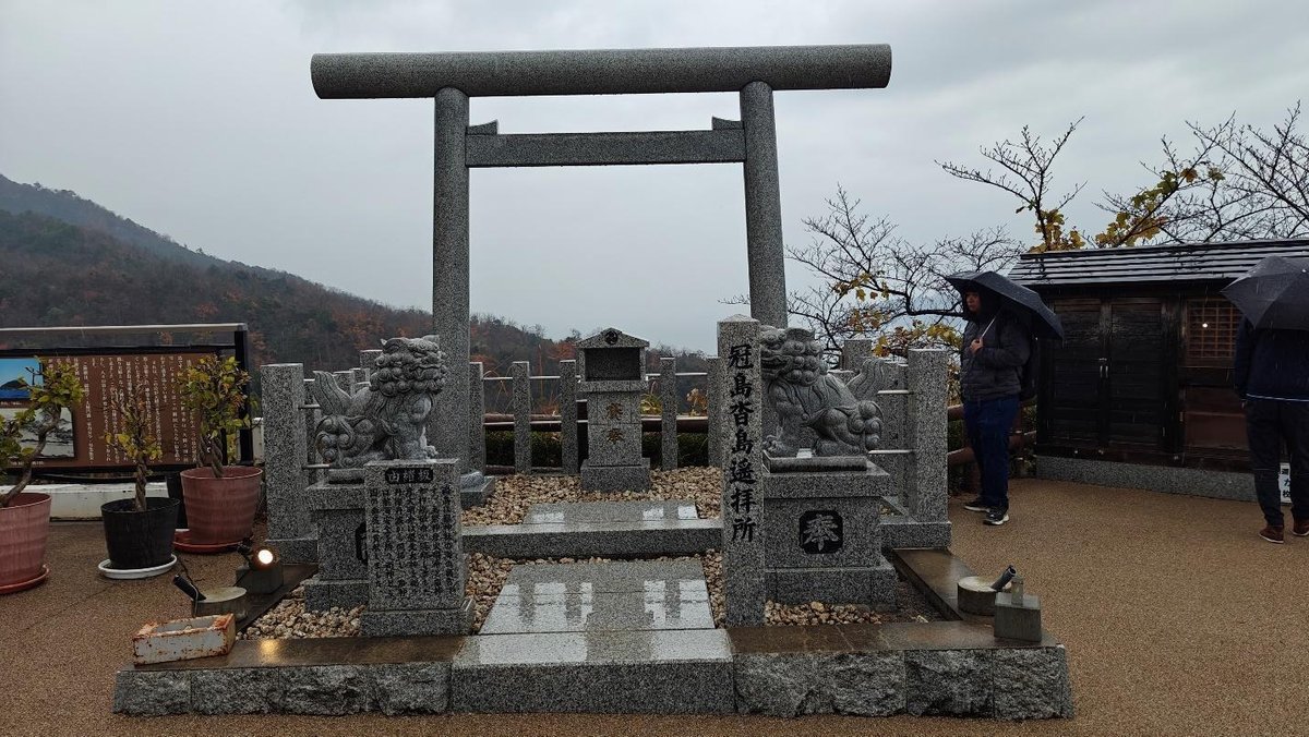 Stone torii gate with guardian statues on a rainy day