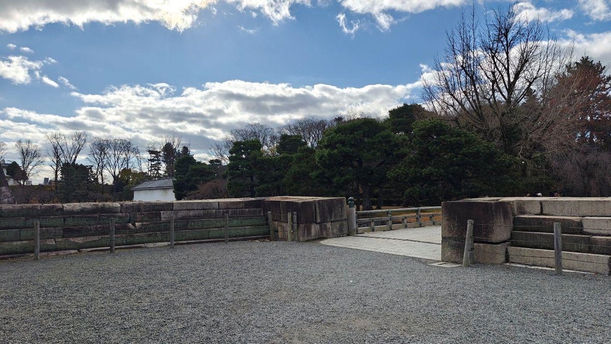 Stone wall and trees under cloudy sky