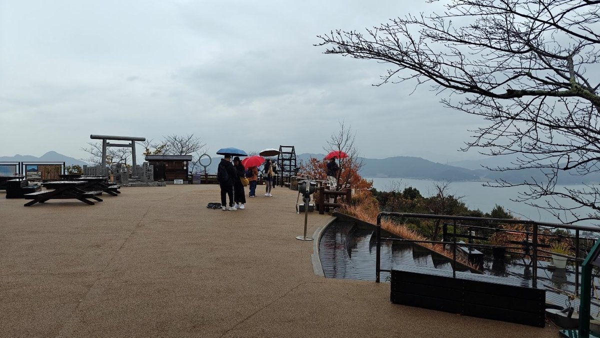 Tourists with umbrellas on scenic viewpoint overlooking bay