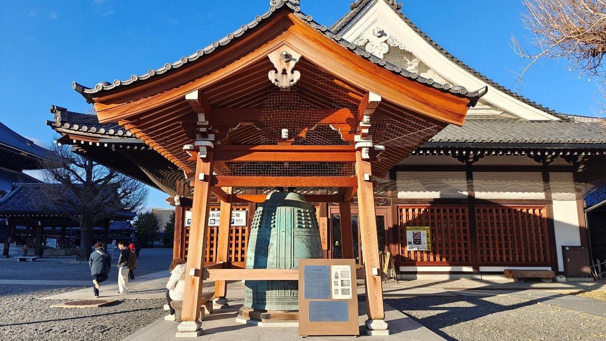 Traditional Japanese temple bell under ornate wooden structure
