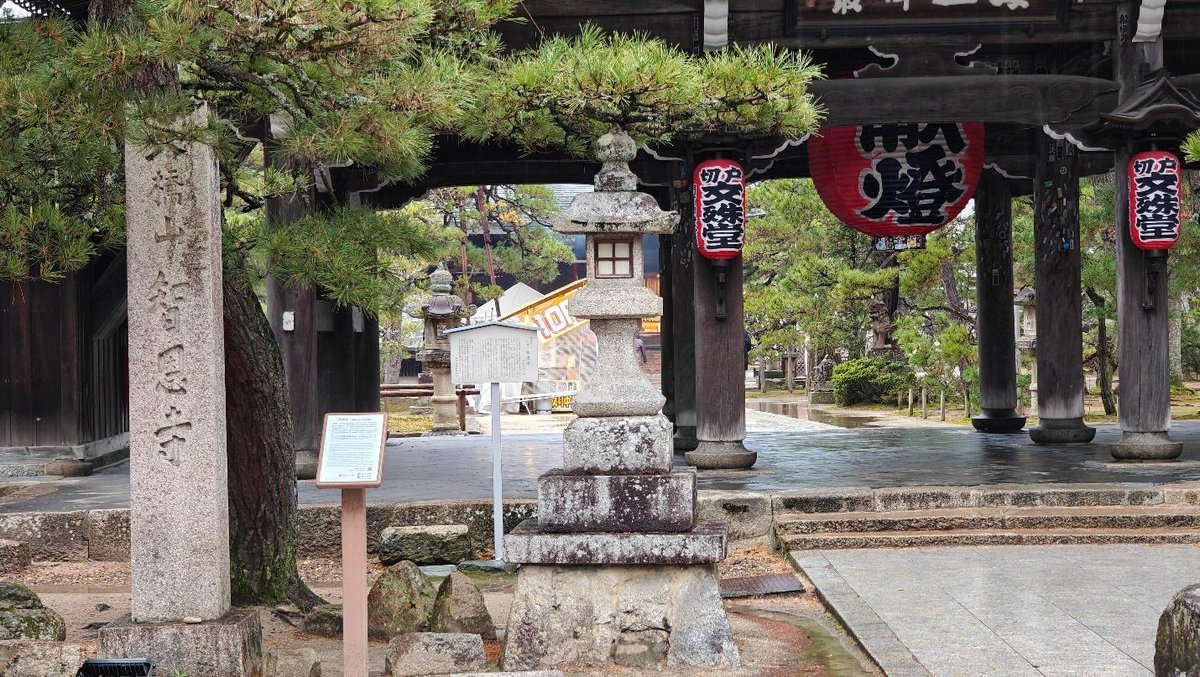 Traditional stone lantern and red lanterns at temple entrance