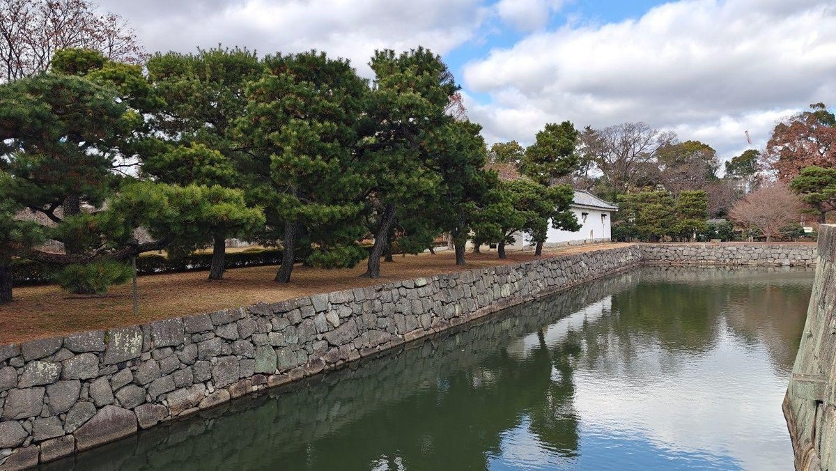 Tranquil moat and trees under cloudy sky
