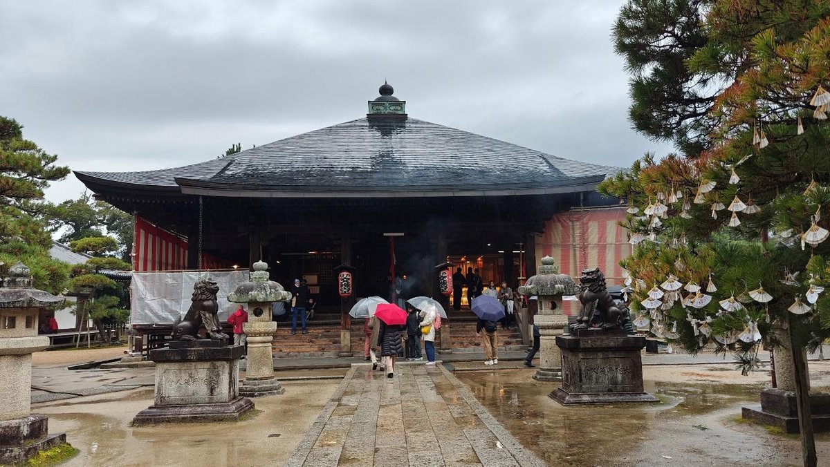 Visitors with umbrellas at a temple on a rainy day