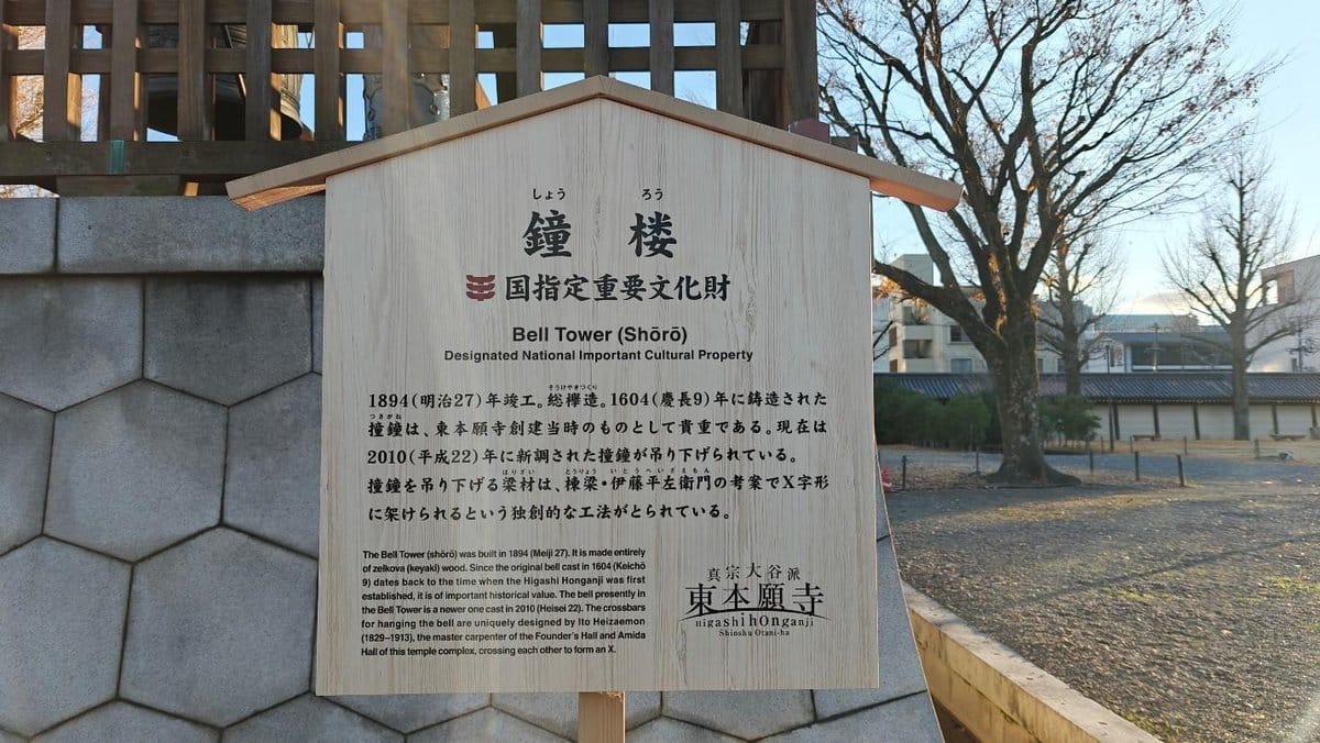 Wooden sign for Bell Tower, trees and building background