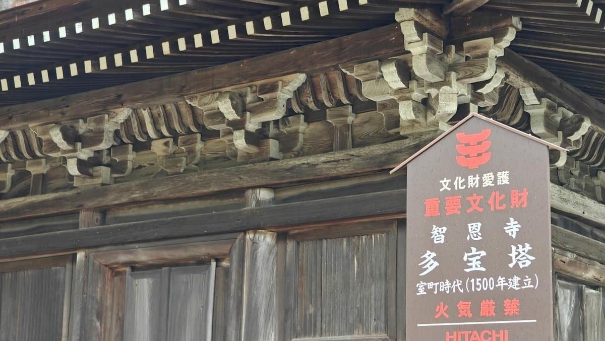 Wooden temple eaves with intricate carvings and a sign