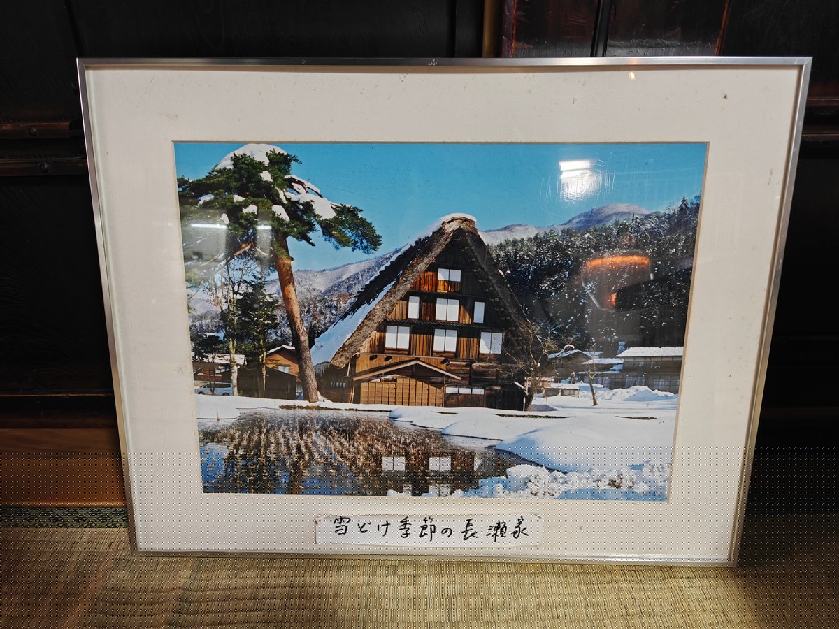 A framed color photograph hand-captioned 雪どけ季節の長瀬家 (Nagase House