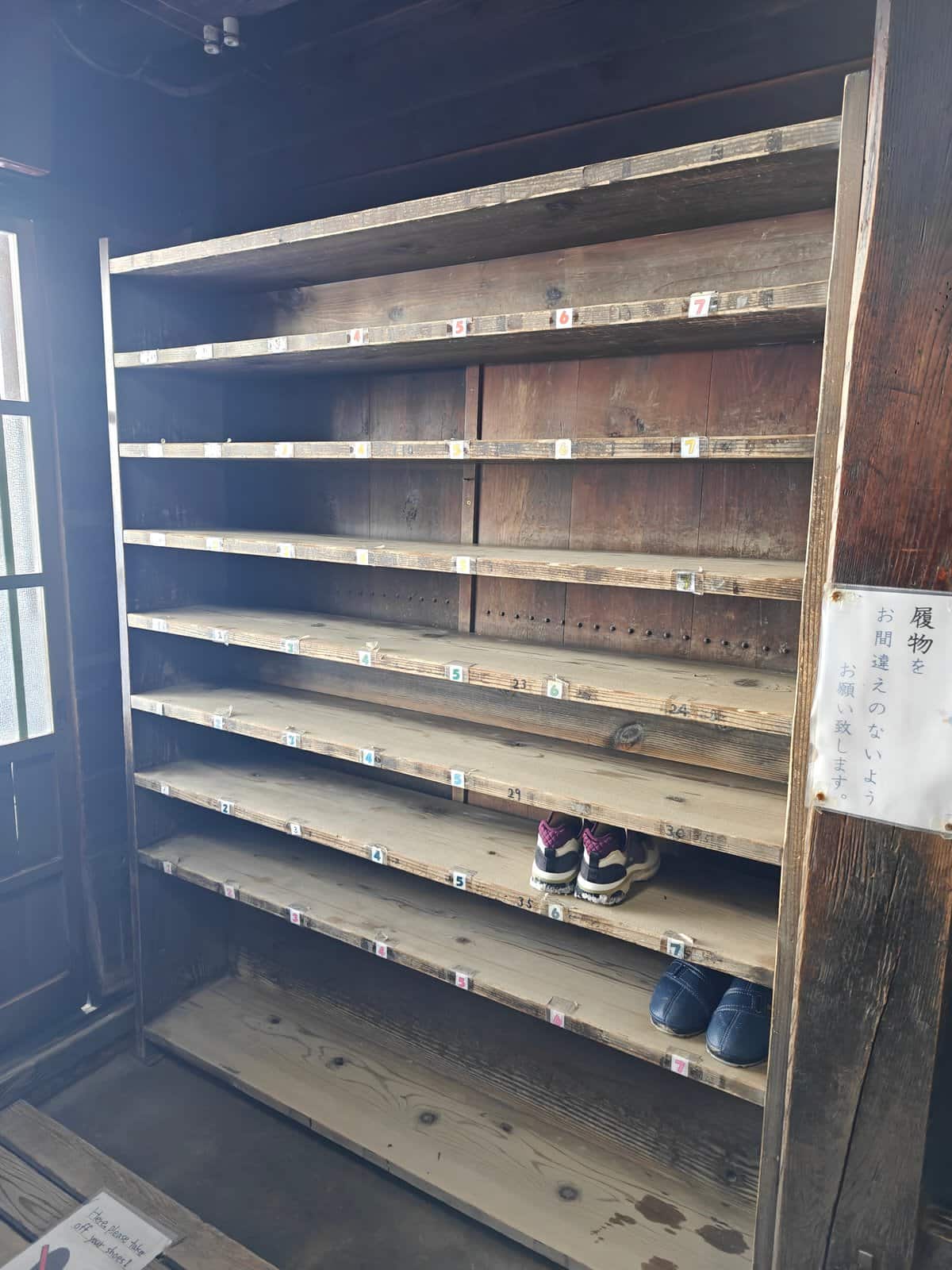 A tall wooden getabako (shoe rack) with many