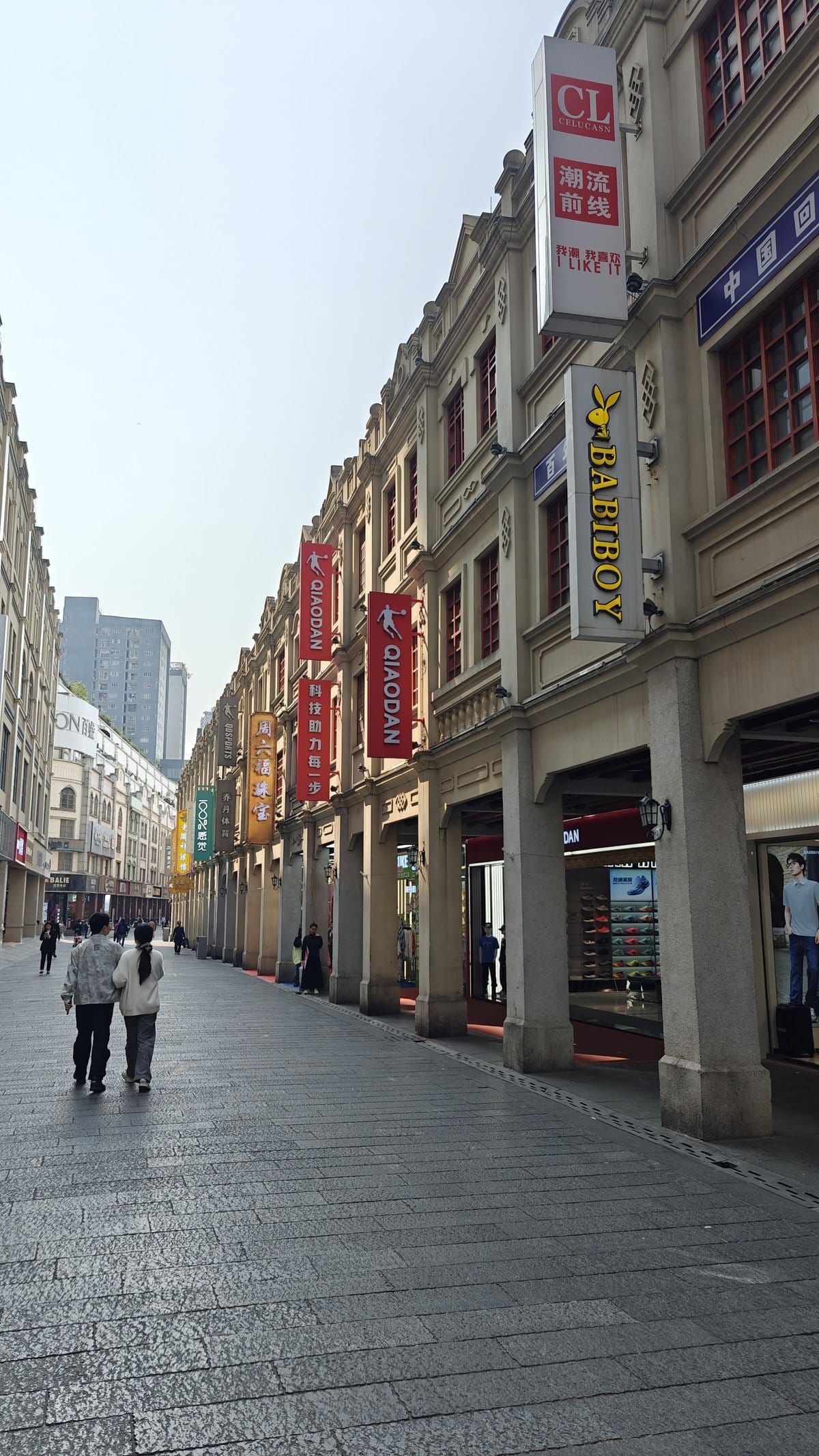 Arcaded walkway with colonial columns, shop banners (Qiaodan,
