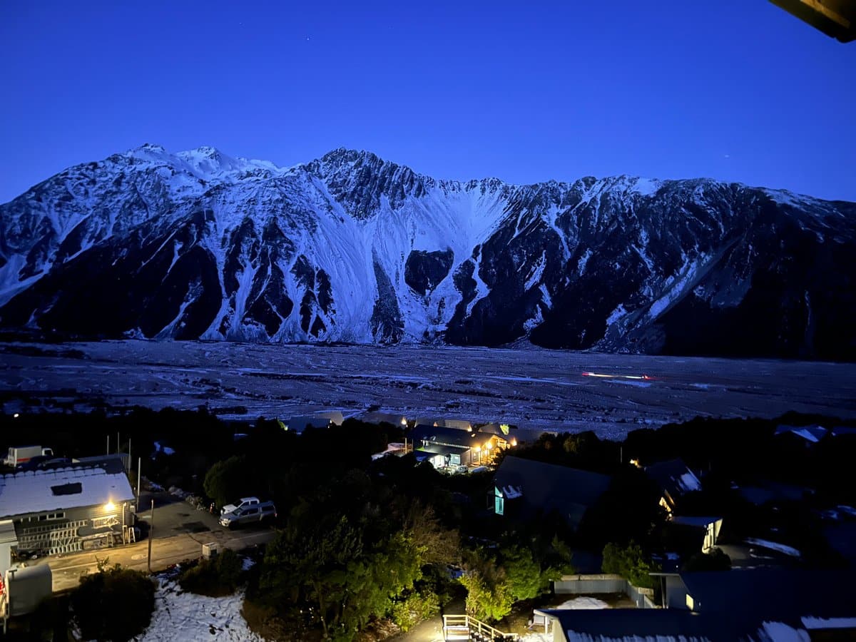 Blue-hour view of the snowy mountains looming over