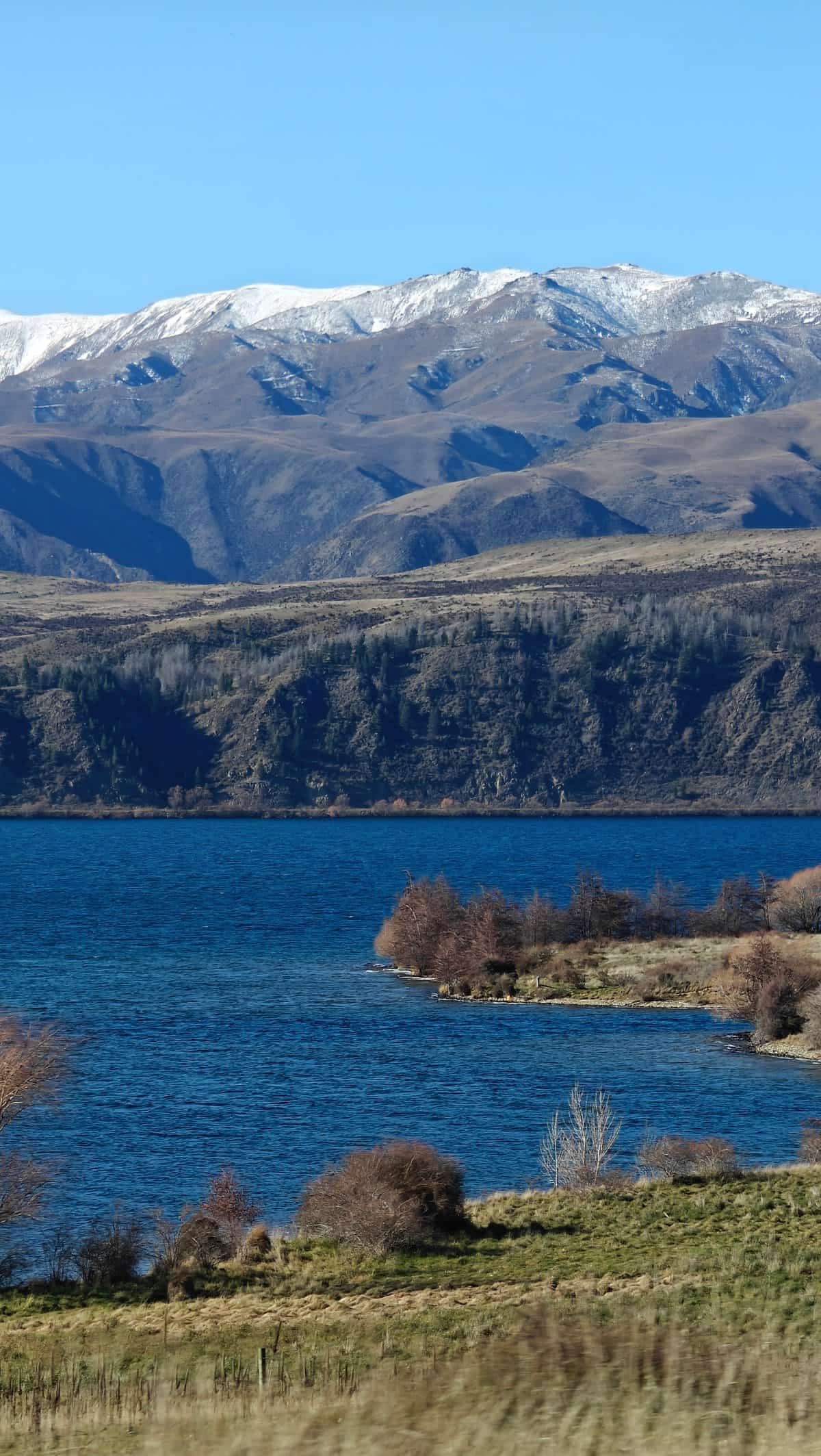 Blue lake with a snow-dusted mountain range rising