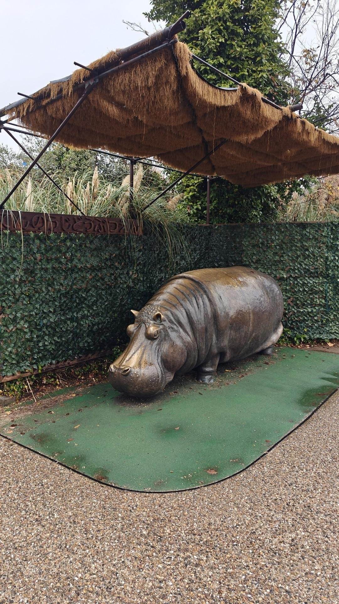 Bronze hippo statue under thatched roof