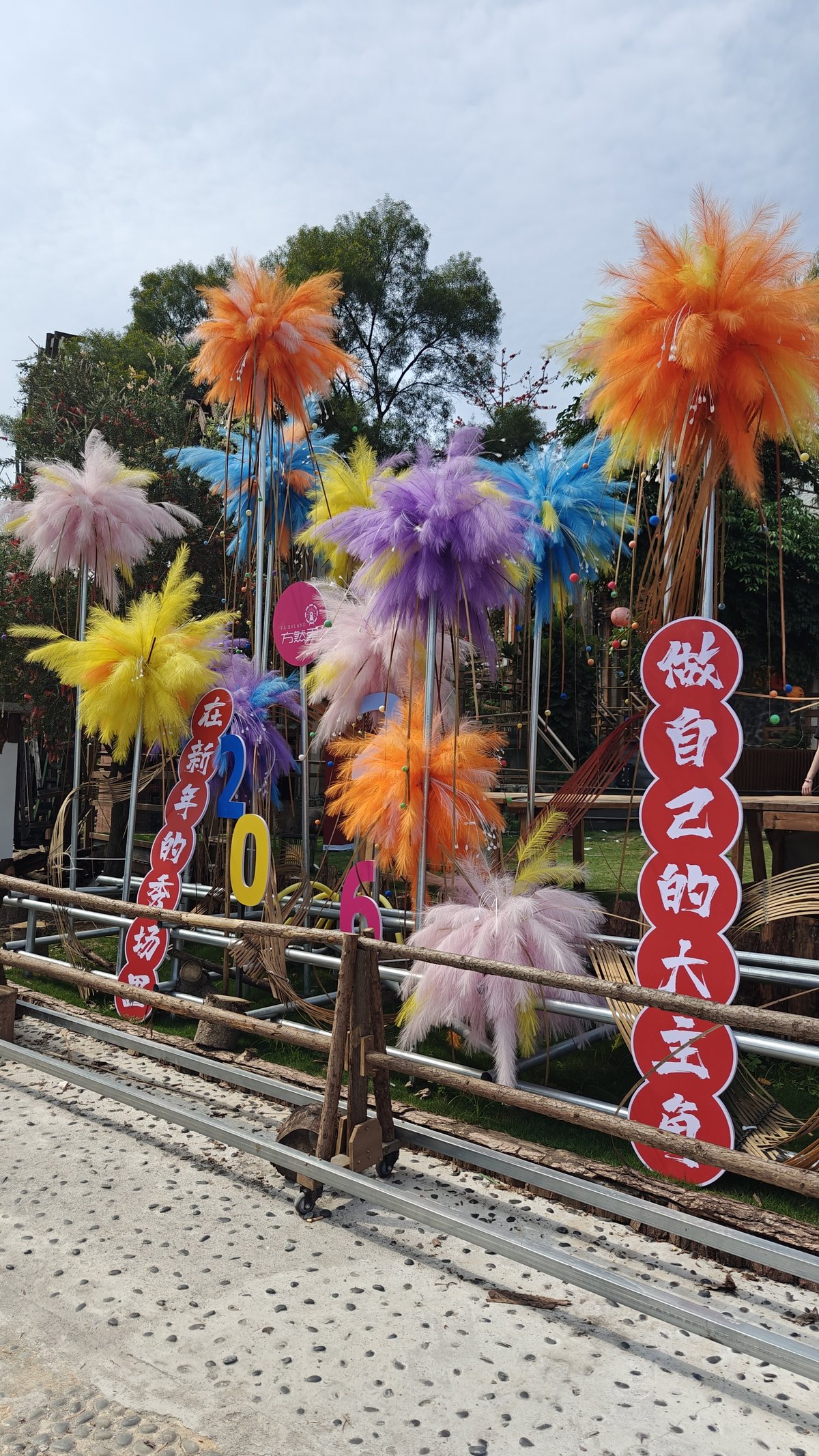Colorful feather/pom-pom decorations on poles with '2026' numbers,