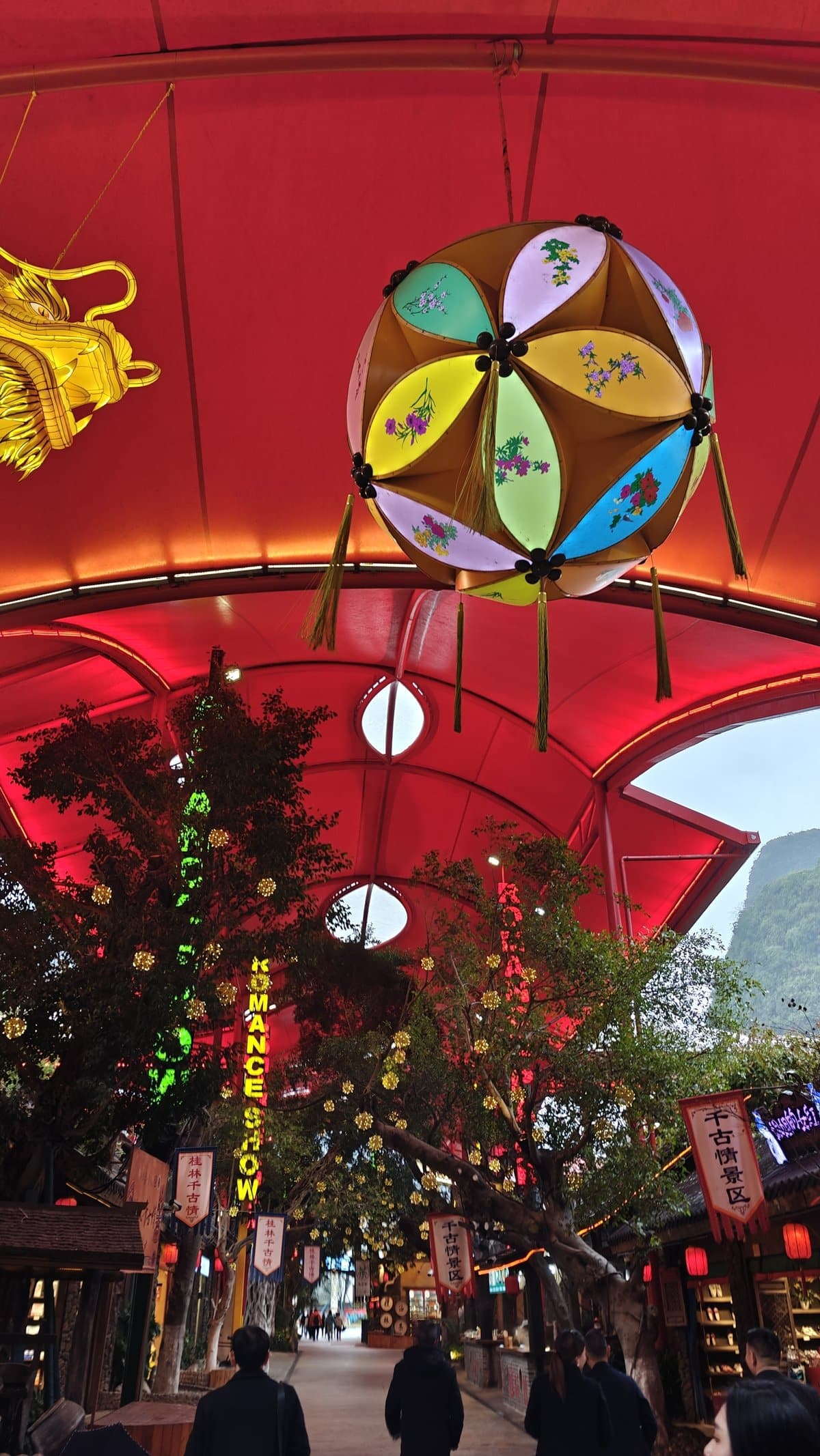 Covered shopping street under red canopy with colorful