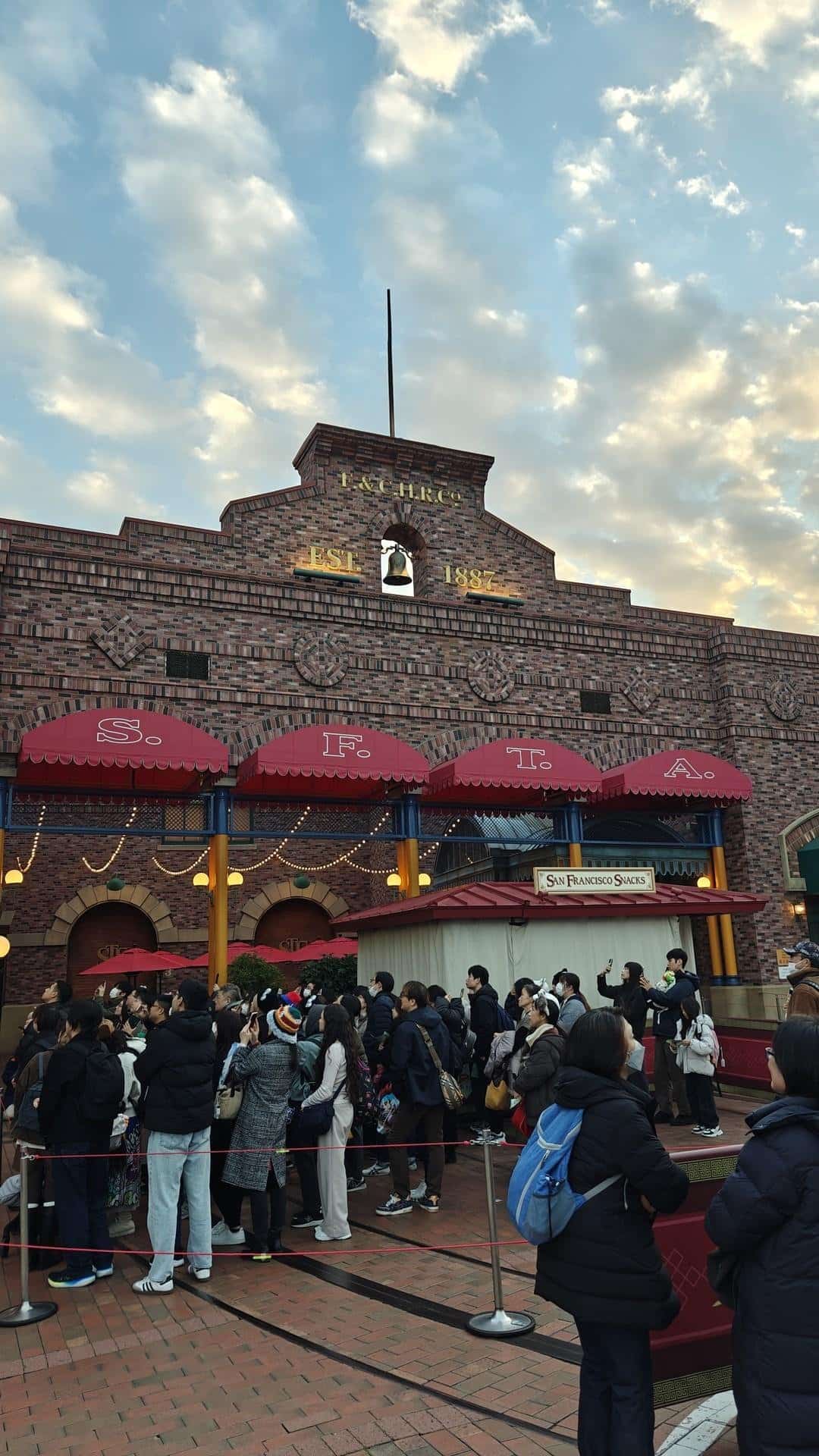 Crowd outside brick building under clouds