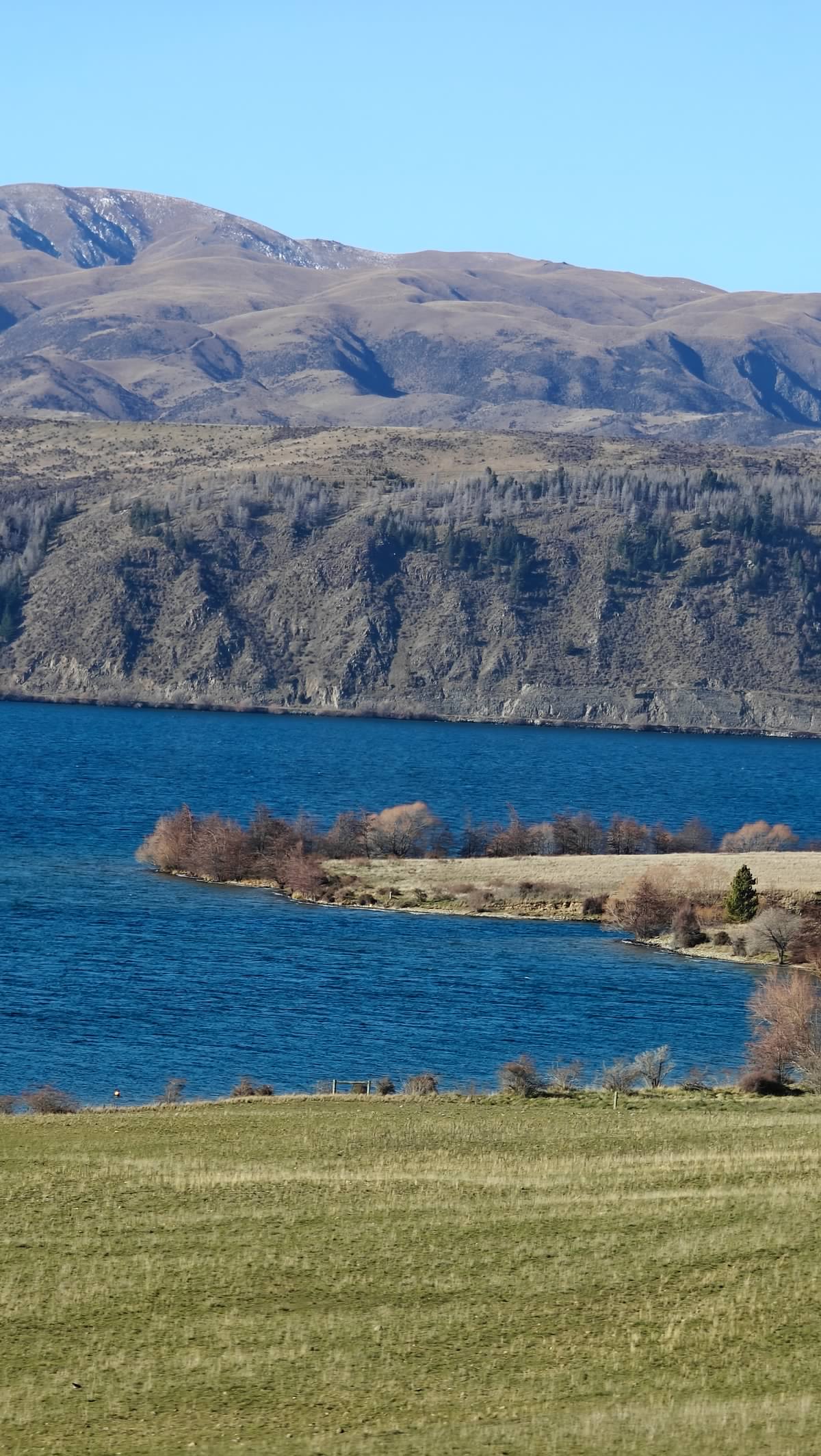 Deep-blue lake below steep dry hills with a