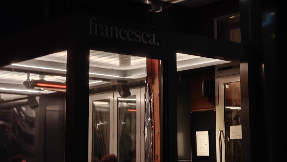 Exterior at night: the lower-case 'francesca.' sign glowing