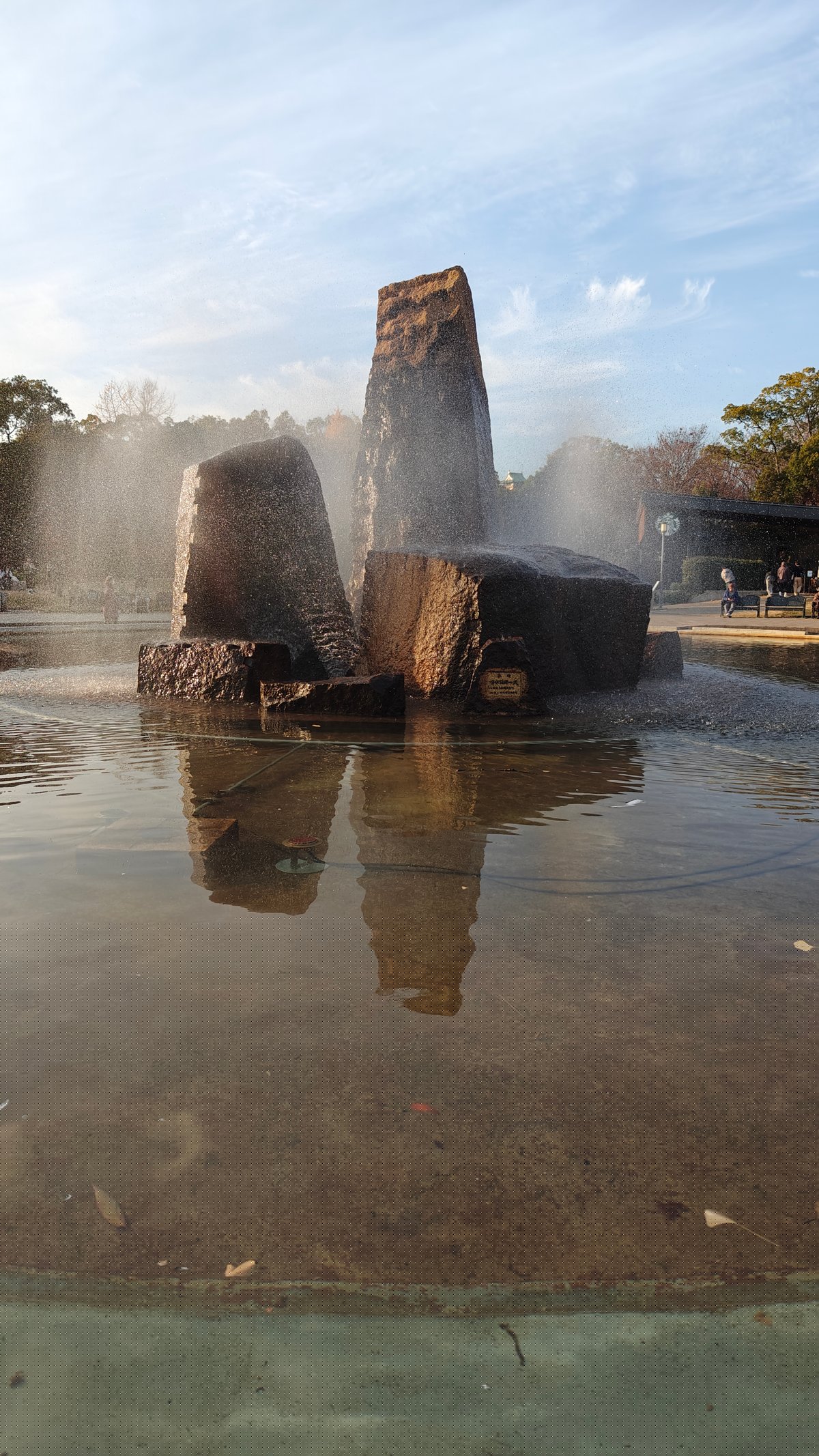 Fountain close-up with stone pillars, mist, water reflection