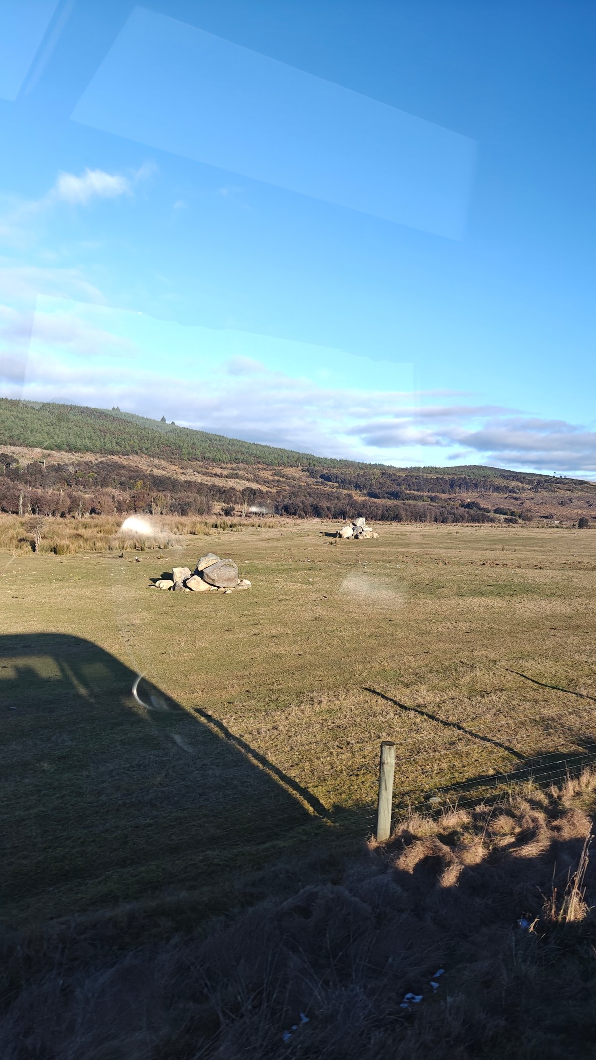 Grassy paddock stretching toward distant fields and hills