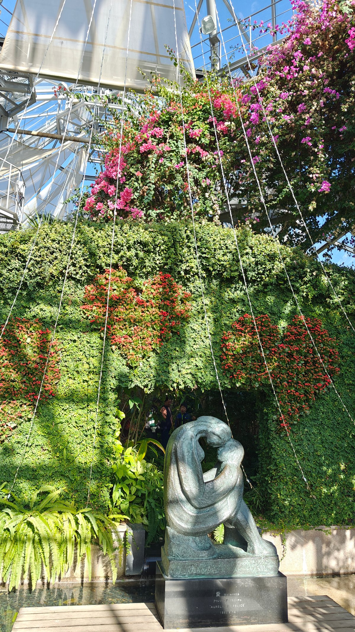 Greenhouse green wall with a stone embracing-figures sculpture