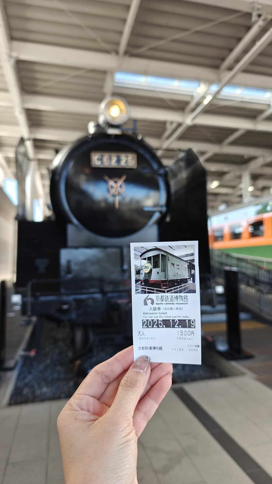 Hand holding museum ticket near train