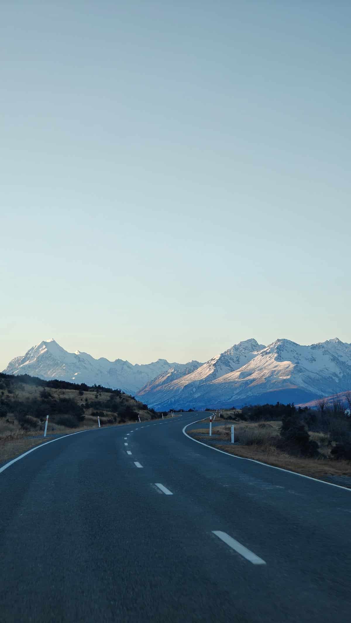 Highway running toward a distant snow-capped range with