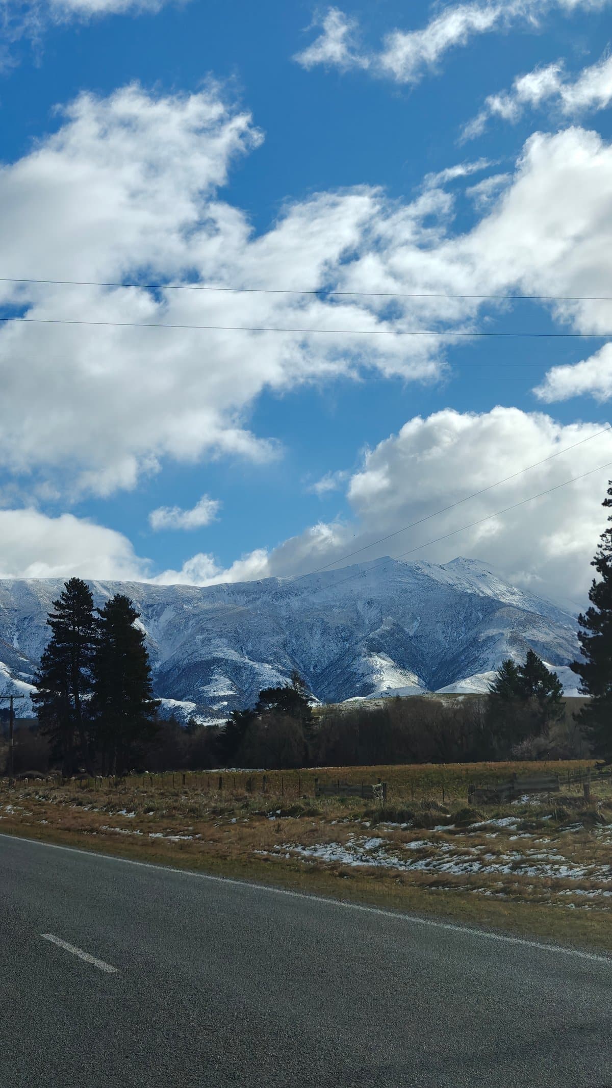 Open road heading toward snow-capped peaks, a stand