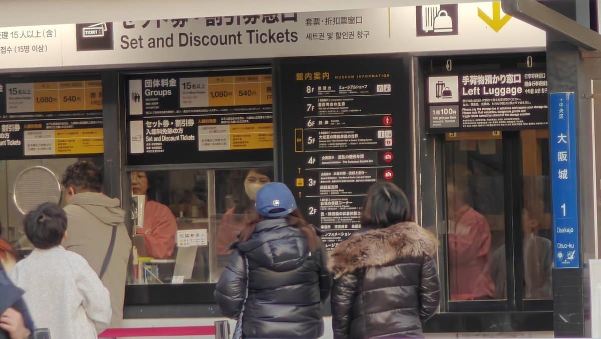 People at ticket counter with signs
