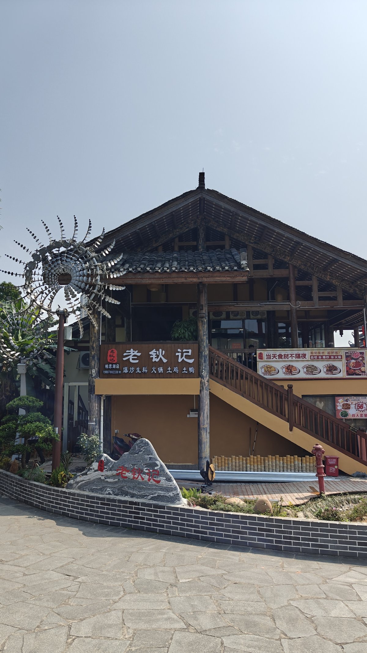 Restaurant building '老钦记' with metal wind sculpture, wooden