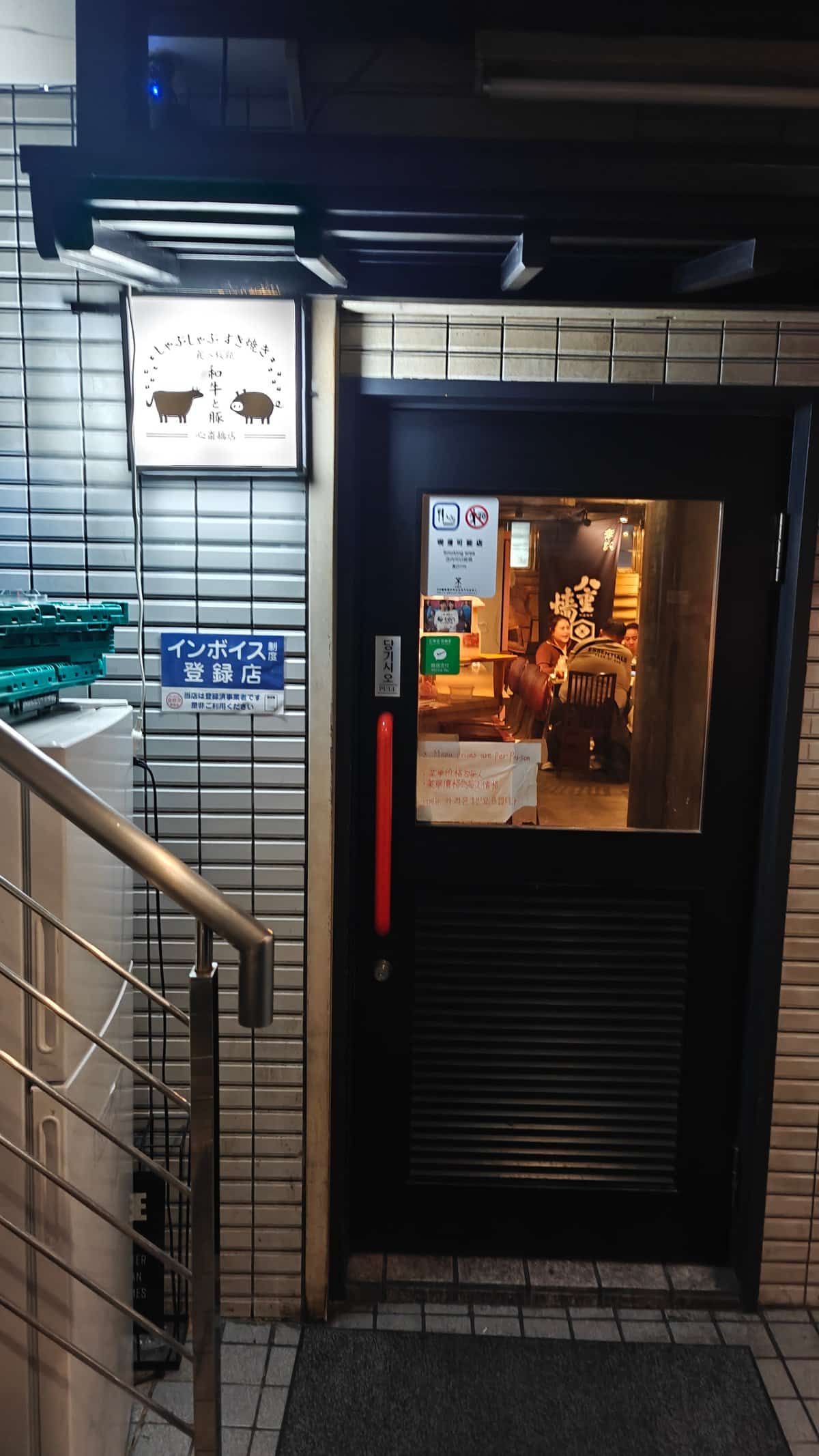 Restaurant entrance down stairs with dark door and
